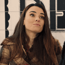 a woman wearing a plaid coat is looking up at something