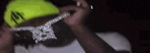 a close up of a man wearing a neon yellow hat and a necklace .