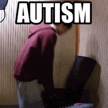 a man in a red hoodie stands in front of a wall with the word autism on it
