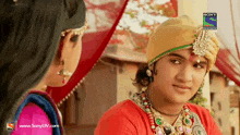 a man in a turban is looking at a woman with a sony television advertisement behind him