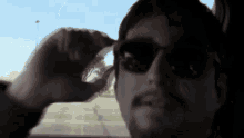 a man with a beard wearing sunglasses looks out the window