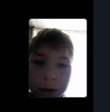 a close up of a young boy 's face on a black screen .