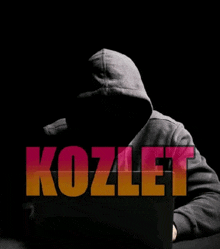 a man in a hooded sweatshirt is sitting in front of a laptop with the word " kozlet " on the screen