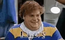 a man in a blue and yellow shirt is smiling with arabic writing on his shirt .