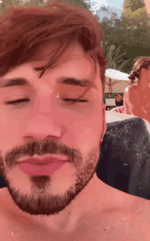 a man with a beard has his eyes closed in front of a woman