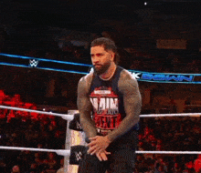 a man in a wrestling ring wearing a shirt that says ' pain next ' on it