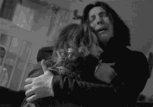 a black and white photo of a man and woman hugging each other .