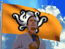 a man in a suit stands in front of a yellow flag with a black octopus on it