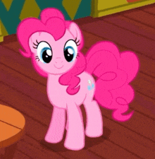 pinkie pie from my little pony standing on a wooden floor .