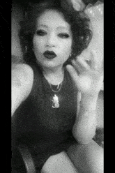 a black and white photo of a woman wearing a necklace that has a cat on it