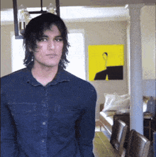 a man in a denim shirt is standing in a living room