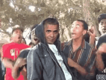 barack obama is wearing a hooded jacket while dancing with a group of people .