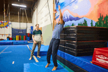 a man is doing a trick in a gym with a mural on the wall that says " hurr "