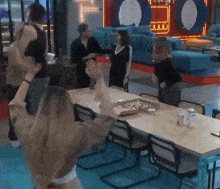 a group of people are standing around a table playing a game of chess .