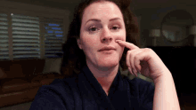 a woman in a blue robe holds her finger to her chin