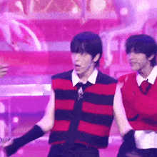 a man in a red and black striped vest is standing on a stage .