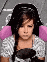 a woman wearing headphones and a striped shirt is sitting in front of a microphone .