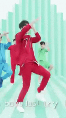 a man in a red suit is dancing in front of a group of people in blue and green .