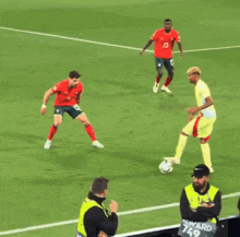 a man in a yellow vest with the word ward on it watches a soccer game