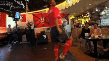 a man in a red shirt with the number 100 on the back is kicking a soccer ball