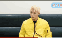 a man is sitting on a couch wearing a yellow jacket .