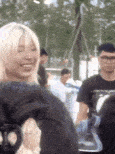 a woman with blonde hair is smiling while standing next to a man in a black shirt .