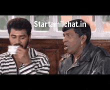 two men are sitting next to each other and one of them is drinking from a cup