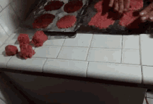 a person is making red cookies on a white counter top