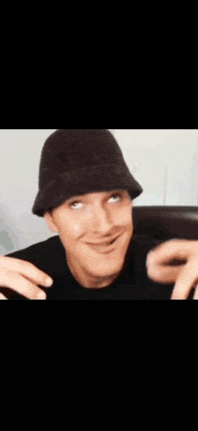 a man wearing a black hat and a black shirt is making a funny face
