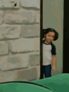a doll is peeking out from behind a brick wall