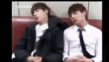 two men in suits and ties are sitting on a couch .