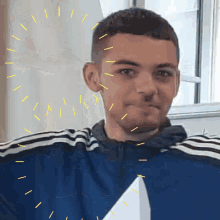a young man wearing a blue adidas jacket is holding a piece of paper