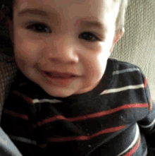 a little boy wearing a striped shirt is smiling for the camera