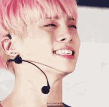 a close up of a young man with pink hair and a microphone in his ear .
