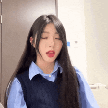 a woman with long hair wearing a blue shirt and a black vest