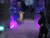 a woman in a white dress is dancing in a dark room surrounded by purple lights .