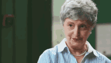 an older woman wearing a striped shirt and pearl necklace