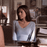 a woman in a light blue sweater is sitting at a desk