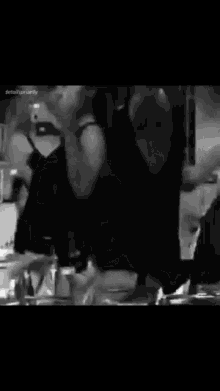 a black and white photo of a group of people dancing in a room .