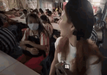 a woman wearing a face mask stands in front of a group of people
