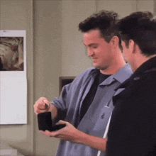 a man in a blue shirt is holding a box with a ring inside of it