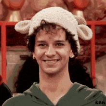 a young man wearing a knitted hat with sheep ears smiles for the camera