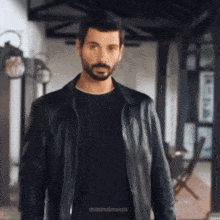 a man with a beard wearing a black leather jacket and a black shirt
