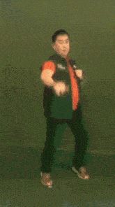 a blurred image of a man in a green vest and orange tie