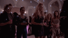 a group of women are standing in a room and one of them is wearing a black dress