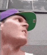 a man wearing a purple hat and a green hat with a qr code on it