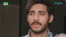 a close up of a man 's face with a green tv logo in the background