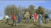 a group of people are dancing in a field with a cardboard box on their backs .