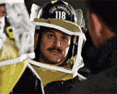 a man with a mustache wearing a helmet with the number 118 on it