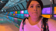 a woman in a white shirt stands in front of a colorful display